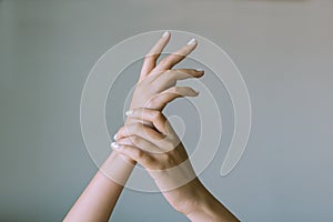 close up of woman hands and arms crossed on bed sheet with delicate soft natural light. Concept of hand care and manicure. white