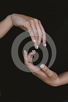 close up of woman hands and arms crossed on dark black background with delicate soft natural light. Concept of hand care and