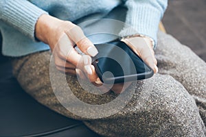 Close up of woman hands with beautiful manicure and white nail polish is holding cell phone. Reading news, surfing the web /