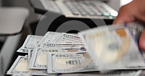 close-up of woman hands counting a stack of hundred-dollar US banknotes.