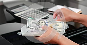 close-up of woman hands counting a stack of hundred-dollar US banknotes.