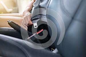 Close up of woman hands fastening or putting seat belt