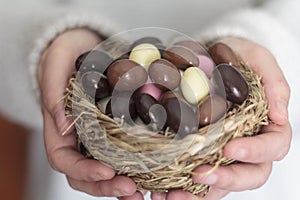 Close up of woman hands holding bird nest with Easter eggs