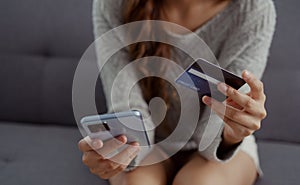 Close up of woman hands holding credit card and smartphone. Young woman paying online using banking entering data shopping order