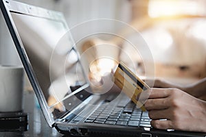 Close up of woman hands holding credit card and using laptop computer notebook with lights orange and copy space design for shoppi