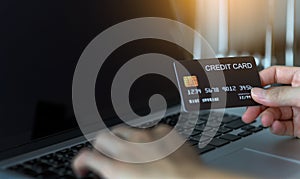 Close up woman hands holding credit card and using laptop shopping purchasing online. e-commerce, internet banking, checking