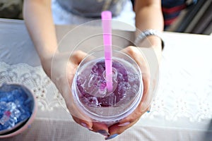 Close up  a woman hands holding a glass of butterfly-pea juice on ice
