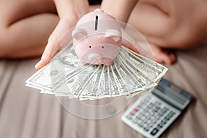 Close-Up Woman Hands is Holding Money Cash and Piggy Bank in Her Bedroom, Pink Piggy Saving, Business Banking and Financial