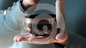 Close-up of woman hands holding and playing on small Tibetan Singing Bowl.