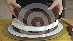 Close up of woman hands making sweet cake with white cream and biscuit.