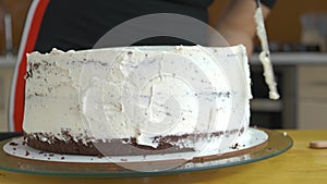 Close up of woman hands making sweet cake with white cream and biscuit.