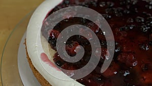 Close up of woman hands making sweet cherry cake with white cream and biscuit.