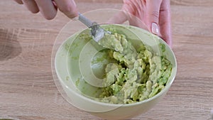Close-up Of Woman Hands Mashing Avocado With Fork In Bowl.