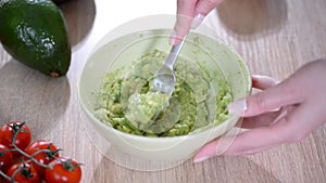 Close-up Of Woman Hands Mashing Avocado With Fork In Bowl