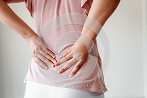 Close-Up of Woman Hands is Massaging Her Waist on  Gray Background, Young Adult having Backache After Home Work.