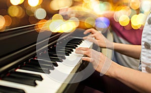 Close up of woman hands playing piano over lights