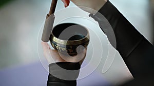 Close-up of woman hands playing on small Tibetan Singing Bowl.