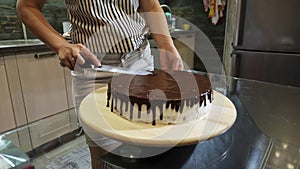 Close-up of woman hands preparing a cake, pouring the chocolate glaze on it.