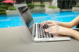 Close up woman hands pressing keyboard on laptop sunny day swimm