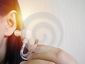 Close-up Of A Woman Hands Putting Hearing Aid In Ear