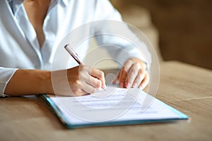 Close up of woman hands signing contract on table