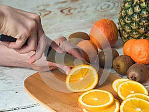 Close up Woman hands slicing orange on chopping board.