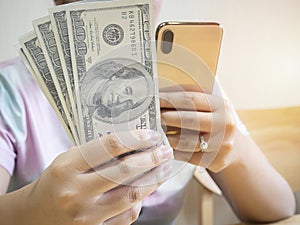 Close up of woman hands with smartphone and us dollar money