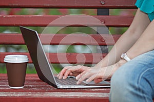 Close up of a woman hands typing in a laptop in park