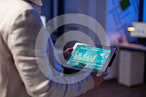 Close-up of woman hands typing on tablet checking financial graphs