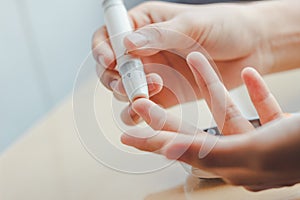 Close up of woman hands using lancet on finger to check blood sugar level by Glucose meter using as Medicine.