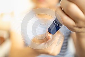 Close up of woman hands using lancet on finger to check blood sugar level by Glucose meter. Use as Medicine, diabetes, glycemia,