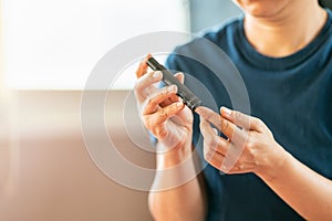 Close up of woman hands using lancet on finger to check blood sugar level by Glucose meter. Use as Medicine, diabetes, glycemia,