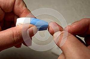 Close up of woman hands using lancet on finger to check HIV status. Blue lancet. Hiv test express