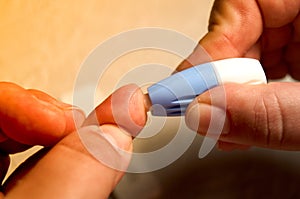 Close up of woman hands using lancet on finger to check HIV status. Blue lancet. Hiv test express