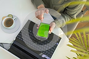 Close up of woman hands using laptop checking smartphone at home