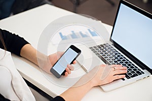 Close Up of woman hands using mobile phone and laptop computer with blank copy space screen for your advertising text