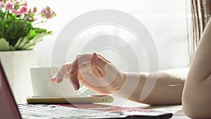 Close up woman hands using smartphone and computer laptop at workplace or work from home