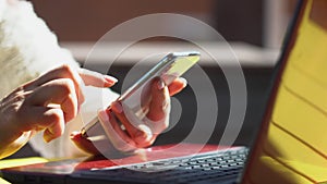 Close up woman hands using smartphone and computer laptop at workplace or work from home