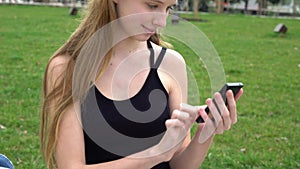 Close-up woman hands using touchscreen phone outdoors in city park