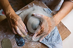 Close up of woman hands working clay making pottery at home. Concept of hobby and creativity at home. Kneading and moistening the