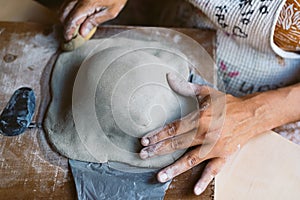 Close up of woman hands working clay making pottery at home. Concept of hobby and creativity at home. Kneading and moistening the