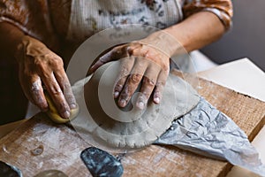 Close up of woman hands working clay making pottery at home. Concept of hobby and creativity at home. Kneading and moistening the