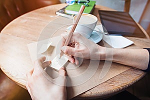 Close up of woman hands writing love notes stickies by wooden pencil. Young beautiful woman drawing love message for a boy friend