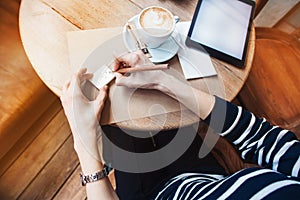 Close up of woman hands writing notes stickies by wooden pencil. Young beautiful woman writing her self schedule task in a cafe. V
