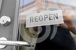 close up of woman hanging reopen banner on door