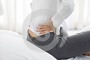 Close up woman have a back pain sitting on bed in bedroom feeling painful