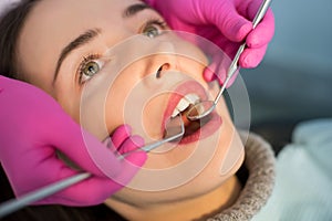 Close up of woman having dental check up in dental office. Dentist examining a patient`s teeth with dental tools