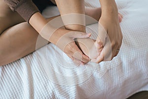 Close up of woman having a heel or foot sole pain,Woman hands giving massage to her foots in bedroom photo