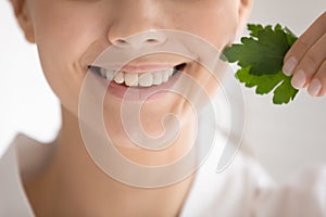 Close up woman with healthy toothy smile holding parsley leaf