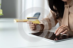Close up woman holding bank credit card and type on digital tablet for shopping online, buying goods or ordering online